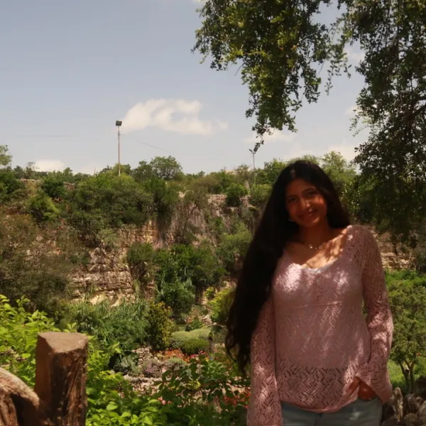 Female smiling with trees in the background.