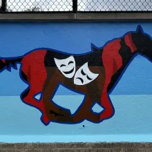 First panel of the mural: mustang with theater drapes and comedy/tragedy masks within.